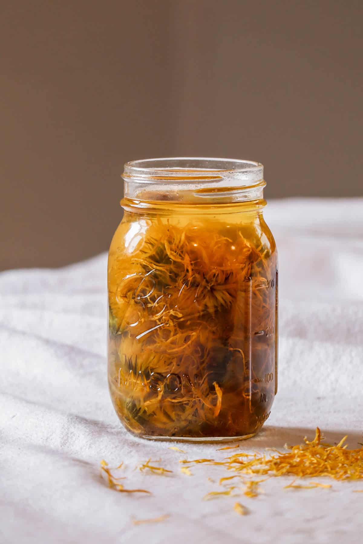 A jar of infusing calendula oil on a table