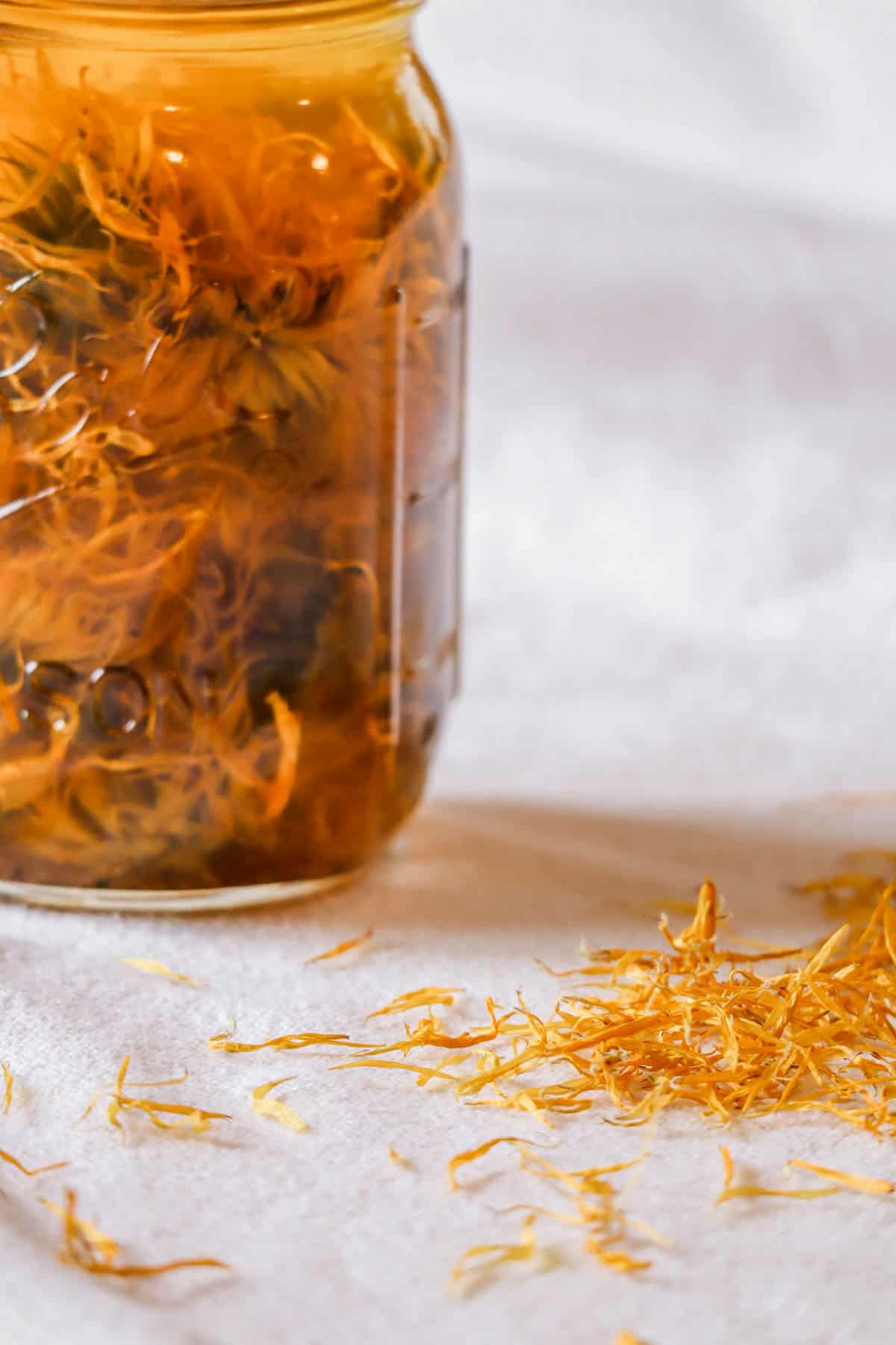 A jar of dried calendula oil infusing
