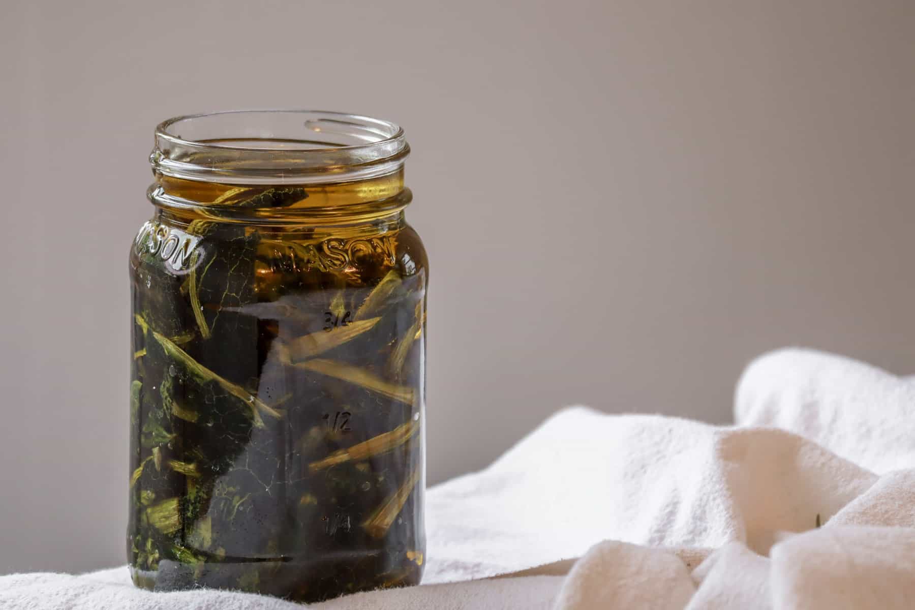 A jar of comfrey oil infusing on a table
