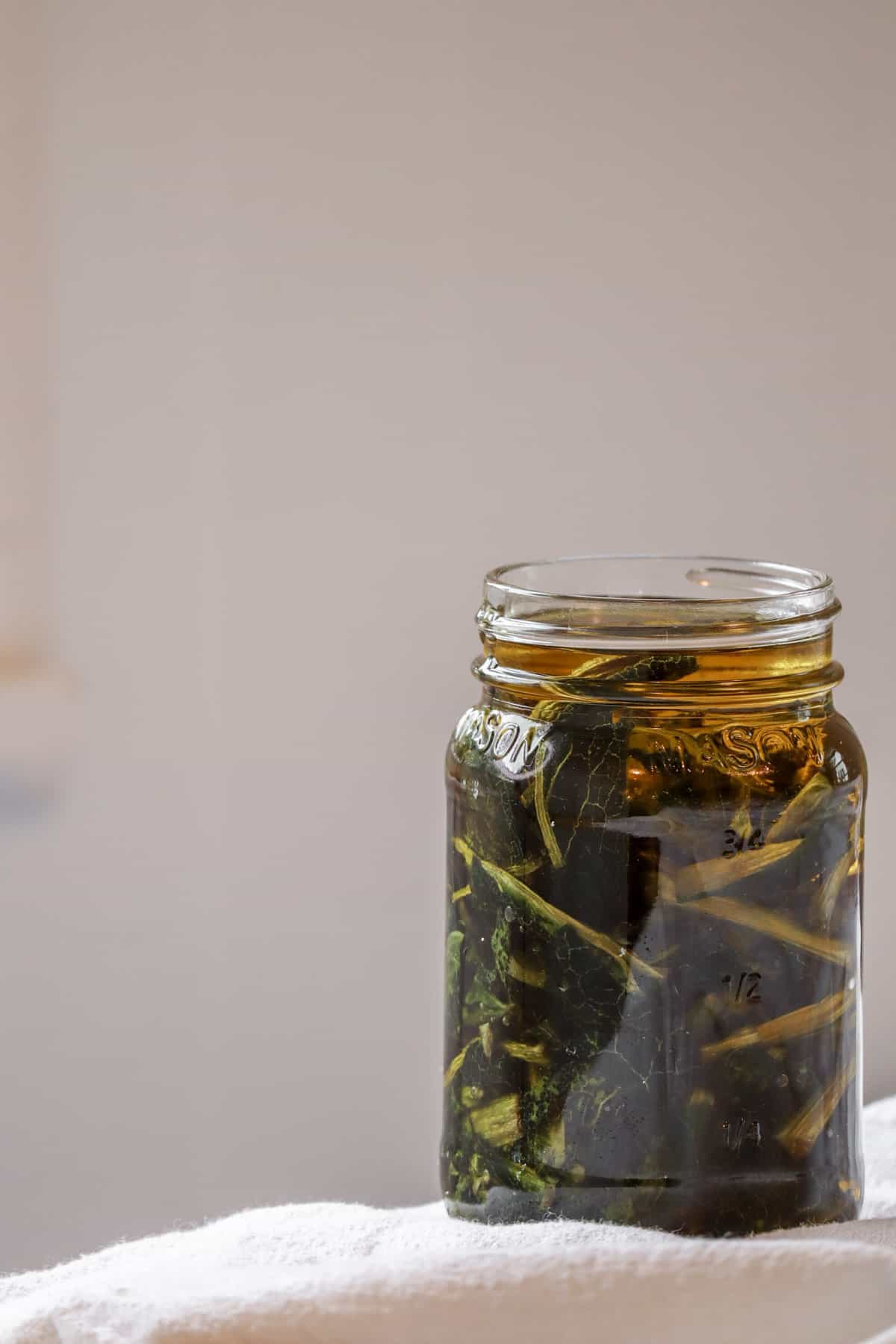 A mason jar of bright green comfrey leaves infusing in oil
