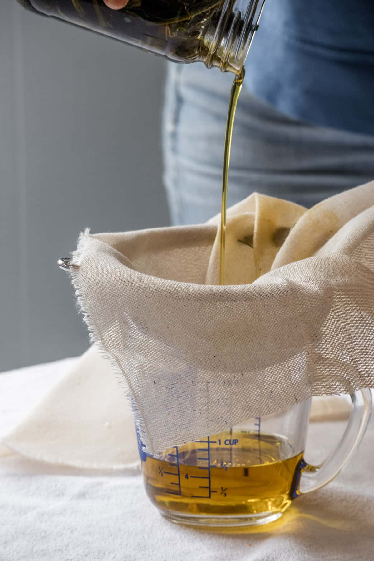 Straining homemade comfrey oil through a cheesecloth