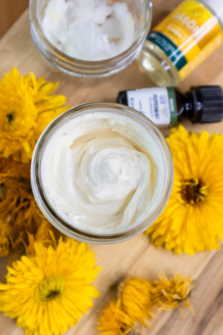 A jar of natural whipped body butter surrounded by calendula flowers