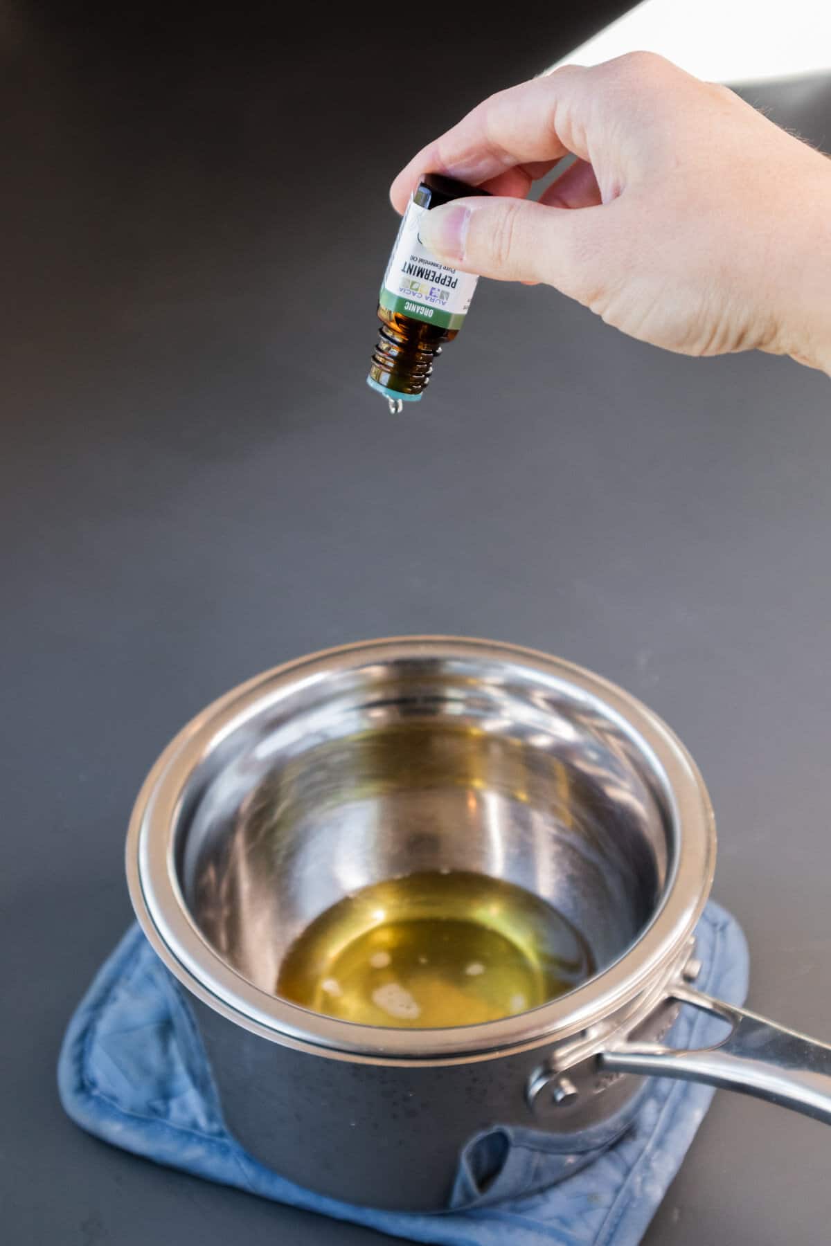 Peppermint essential oil being added to homemade lip balm with shea butter