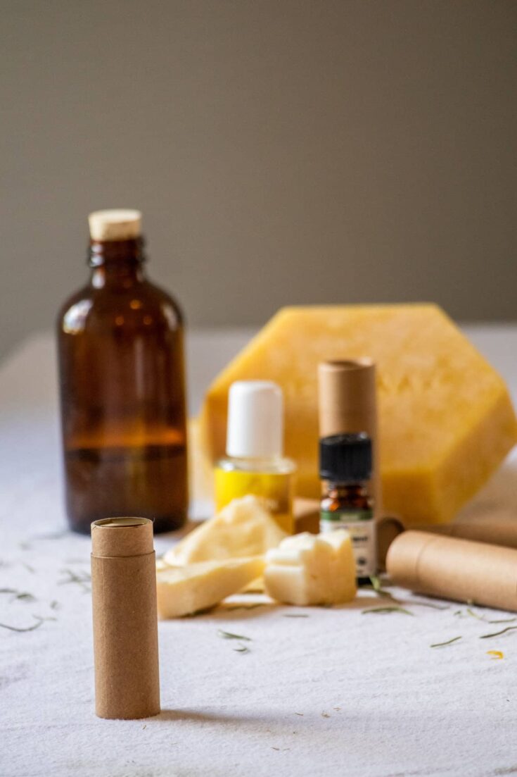A tube of DIY olive oil lip balm on a table with ingredients