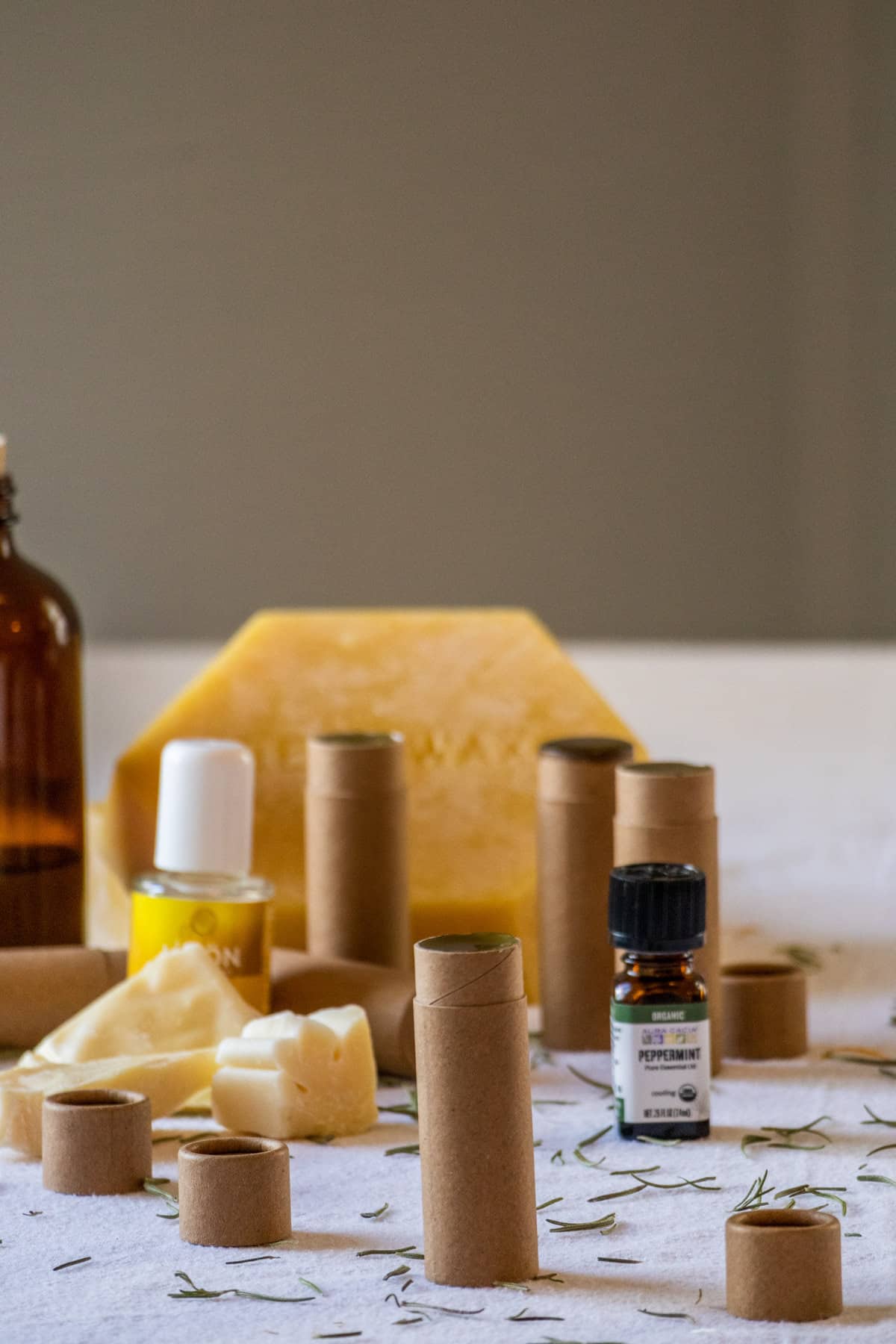 Tubes of homemade olive oil lip balm on a table with ingredients