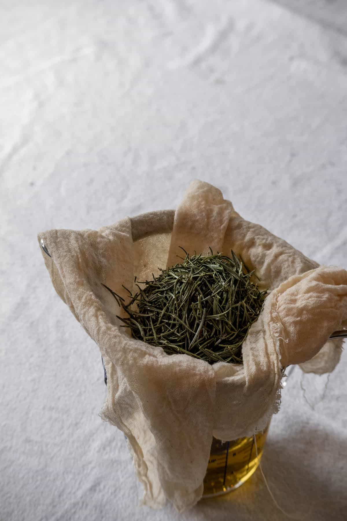 Rosemary oil filtering through a cheesecloth