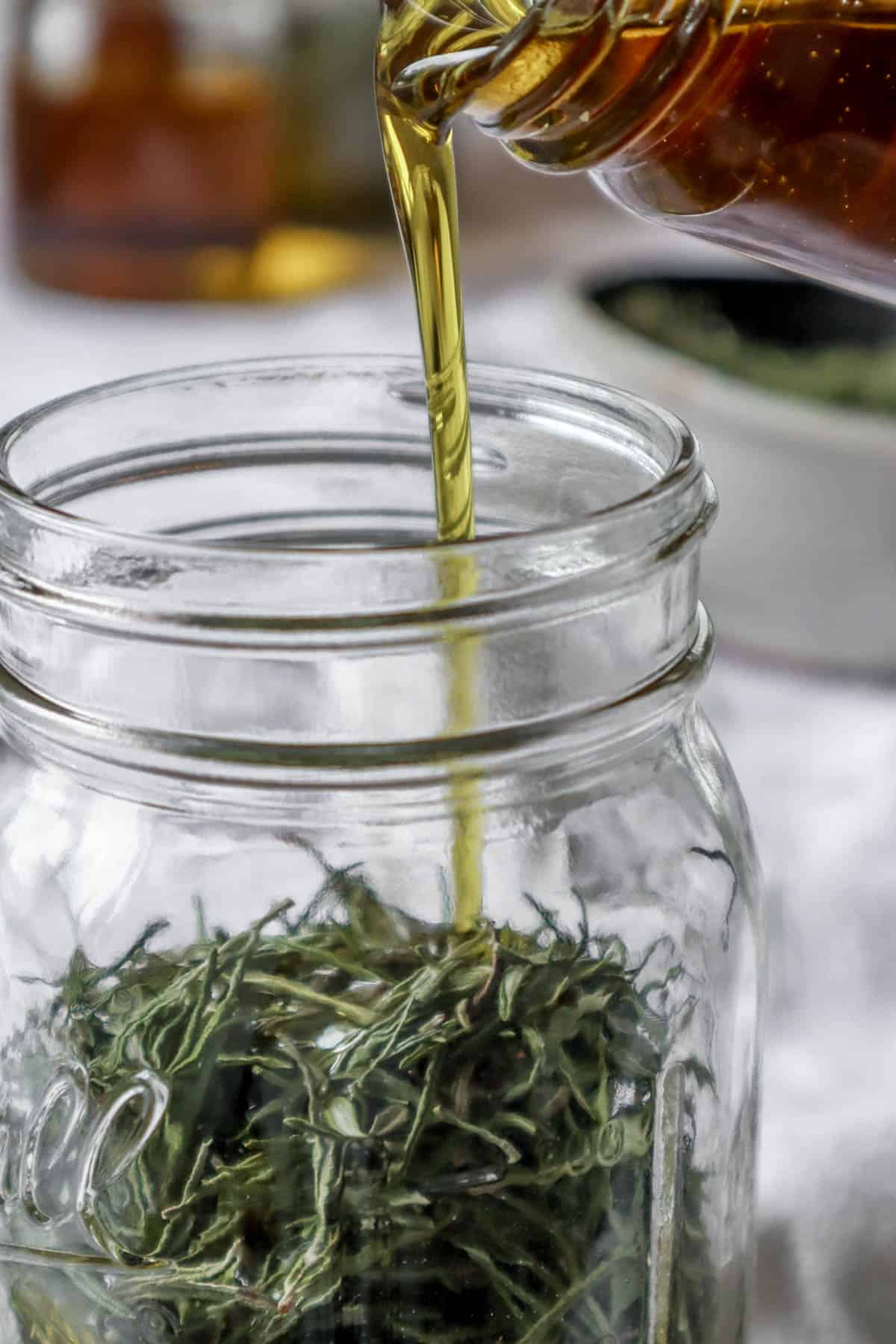 Oil being poured into a jar of dried rosemary