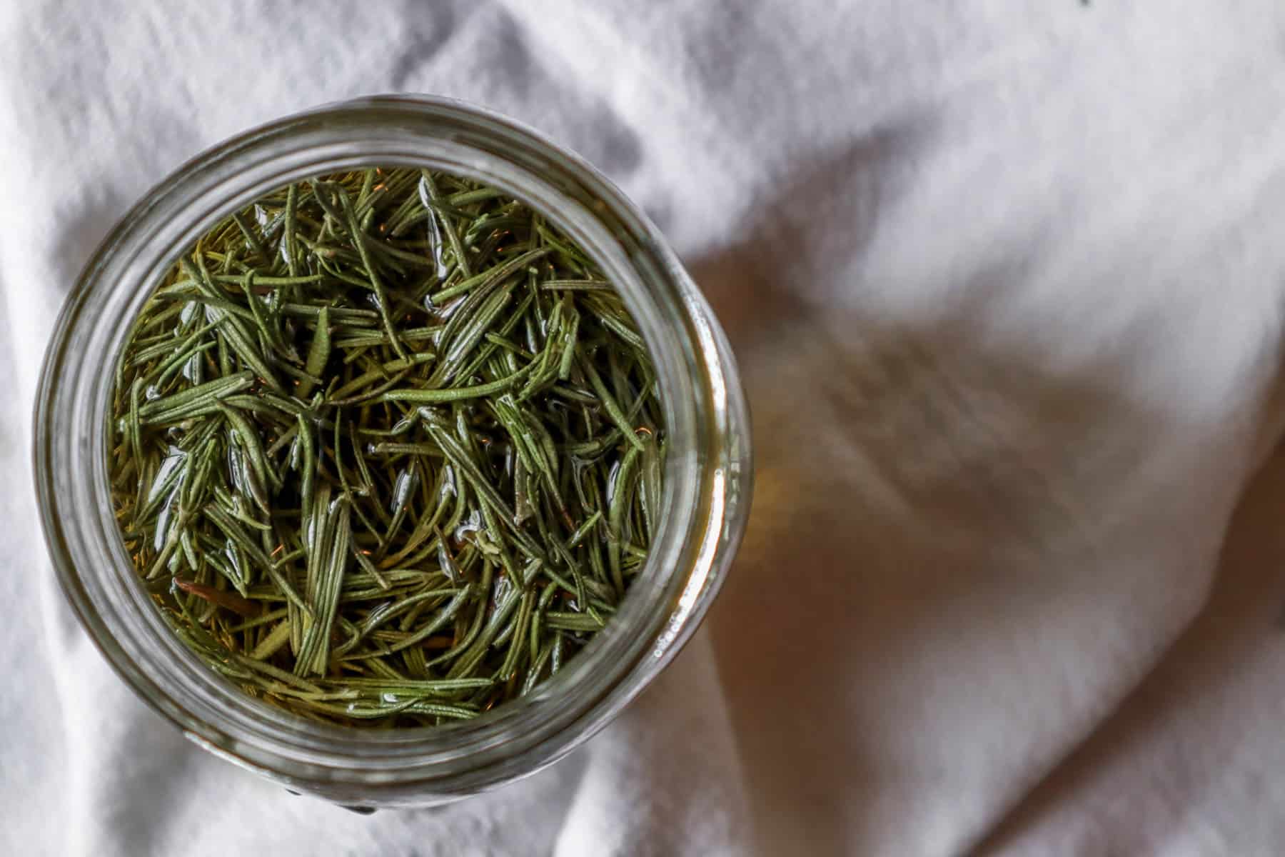 A jar of rosemary oil infusing