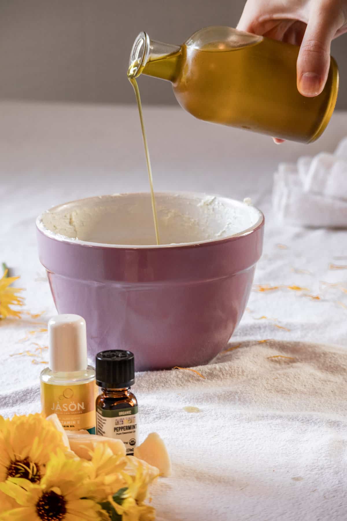 Oil being poured into a bowl of body butter