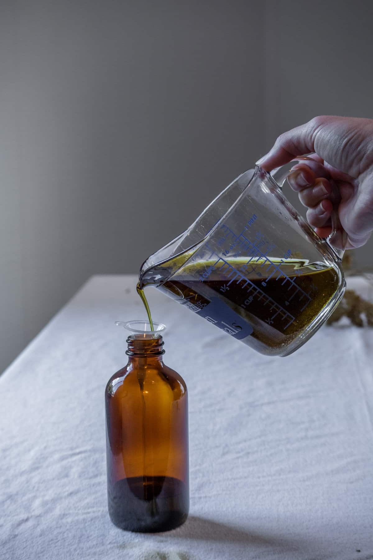 Yarrow oil being poured into an apothecary jar